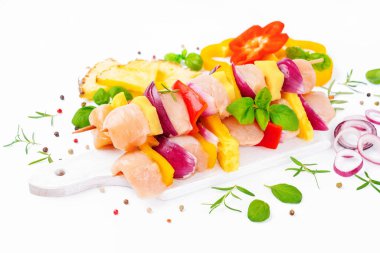 Skewers with pieces of raw meat, red, yellow pepper.Top view.Chicken Skewers breast fillet meat.Uncooked meat skewer.Raw pieces of chicken skewers with pepper onion and pineapple white background.