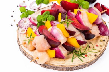 Skewers with pieces of raw meat.Top view.Chicken Skewers breast fillet meat.Raw chicken meat skewers with vegetables,plums,yellow pepper,onions,with spices,herbs white background.Uncooked meat skewer.