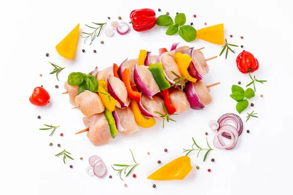 Raw chicken skewers with vegetables,peppers,onions,on a white background.Chicken Skewers breast fillet meat.Uncooked mixed meat skewer.Skewers with pieces of raw meat,red,yellow,green pepper.Top view.