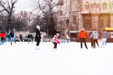 04.01.2022 Budapeşte. Aile kış sporu, spor ve eğlence. Mutlu küçük kız ve oğlan kışın paten kaymayı öğreniyor..