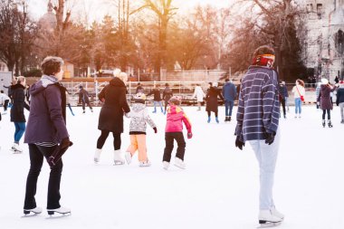 Family winter sport.Soft,Selective focus.People ride on the skating rink on ice rink.Outdoor.Happy family spending time together at outdoor ice skating rink.Sports fun pastime.