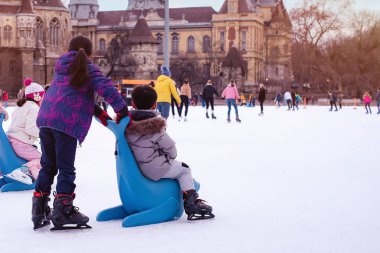 04.01.2022.Budapest.Happy little boy and girl learning to skate in winter.Hobbies and Leisure.Winter sports.Family winter sport.Holiday and seasonal concept.Activity,Adult,Child,Childhood, Daughter.