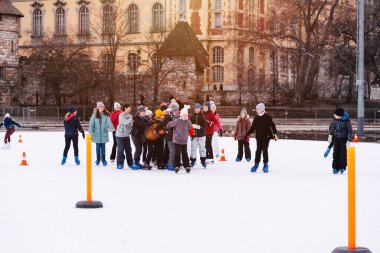 04.01.2022 Budapeşte. Çocuklar ve yetişkinler kış günü açık havada buz pateni pistine giderler. Aile kış sporu. Yumuşak, seçici odaklanma. Açık hava. Kış sporu..