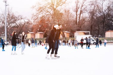 04.01.2022 Budapeşte. Aile kış sporu, spor ve eğlence. Mutlu küçük kız ve oğlan kışın paten kaymayı öğreniyor..