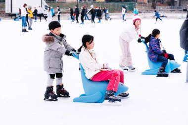 04.01.2022.Budapest.Winter sports.Family winter sport.Holiday and seasonal concept.Activity,Adult,Child,Childhood, Daughter.Happy little boy and girl learning to skate in winter.Hobbies and Leisure.