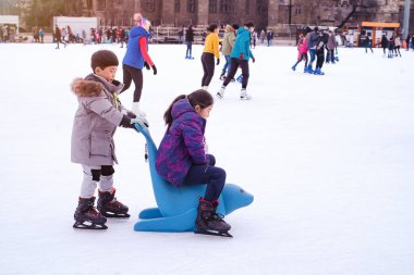 04.01.2022.Budapest.Winter sports.Family winter sport.Holiday and seasonal concept.Activity,Adult,Child,Childhood, Daughter.Happy little boy and girl learning to skate in winter.Hobbies and Leisure.