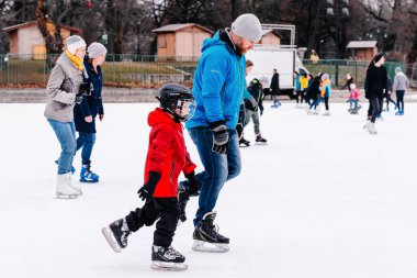 04.01.2022.Budapest.Family winter sport.Soft,Selective focus.People ride on the skating rink on ice rink.Outdoor.Happy family spending time together at outdoor ice skating rink.Sports fun pastime.