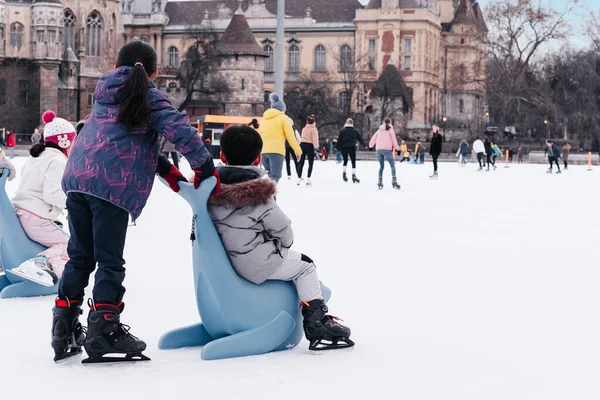 04.01.2022.Budapest.Winter sports.Family winter sport.Holiday and seasonal concept.Activity,Adult,Child,Childhood, Daughter.Happy little boy and girl learning to skate in winter.Hobbies and Leisure.