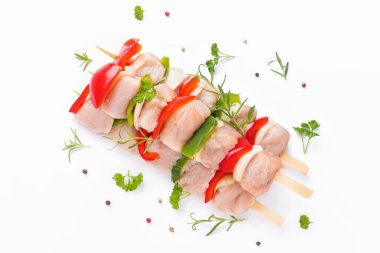 Raw turkey skewers with vegetables, peppers, onions on a white background.Top view.Skewers with pieces of raw meat, red, and green pepper, on white background.Uncooked mixed meat skewer with peppers.