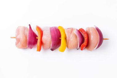 Uncooked mixed meat skewer with peppers.Raw chicken leg meat skewers with vegetables, peppers, onions, on a white background.Skewers with pieces of raw meat, red, yellow and green pepper.Top view.