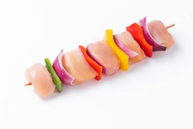 Uncooked mixed meat skewer with peppers.Top view.Skewers with pieces of raw meat, red, yellow and green pepper.Raw chicken skewers with vegetables, peppers, onions, on a white background.