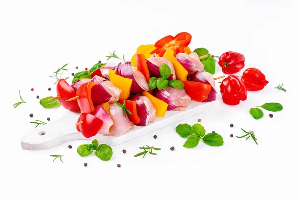 Skewers with pieces of raw meat, red, yellow pepper.Top view.Chicken Skewers meat.Raw chicken leg meat skewers with vegetables,peppers, onions,white background.Uncooked mixed meat skewer with peppers.
