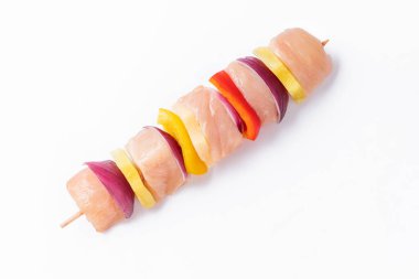 Top view.Skewers with pieces of raw meat, red, yellow and green pepper.Raw pieces of chicken skewers with pepper onion and pineapple on a white background.Uncooked mixed meat skewer with peppers.