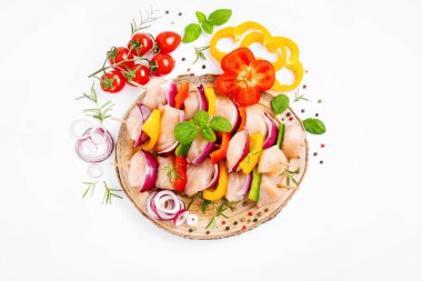 Raw chicken skewers with vegetables,peppers,onions,on a white background.Chicken Skewers breast fillet meat.Uncooked mixed meat skewer.Skewers with pieces of raw meat,red,yellow,green pepper.Top view.