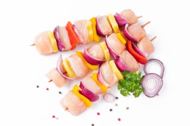 Top view.Skewers with pieces of raw meat, red, yellow and green pepper.Raw pieces of chicken skewers with pepper onion and pineapple on a white background.Uncooked mixed meat skewer with peppers.