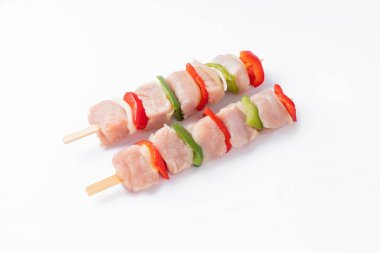 Raw turkey skewers with vegetables, peppers, onions on a white background.Top view.Skewers with pieces of raw meat, red, and green pepper, on white background.Uncooked mixed meat skewer with peppers.