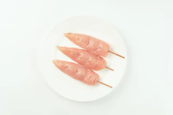 stock image Chicken skewers.Food concept.Skewers from raw chicken meat inner fillet on a white plate for a supermarket on a white background..Ogranic food,healthy eating.Food for retail.Top view.