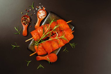 Siyah arka planda taze bitkilerle marine edilmiş taze tavuk fileto şişleri... yiyecek konsepti. Tasarımcılar için tavuk eti. Tavuk göğsü filletsTop görünümü..