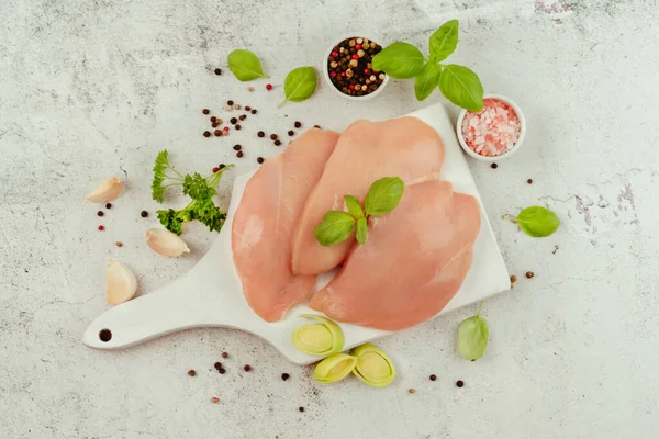 Raw fresh chicken fillet on a gray background with fresh herbs.Raw chicken meat.Copy space.Food for retail.Ogranic food,healthy eating.Food concept.Top view.Chicken breast Fillets.Close up.