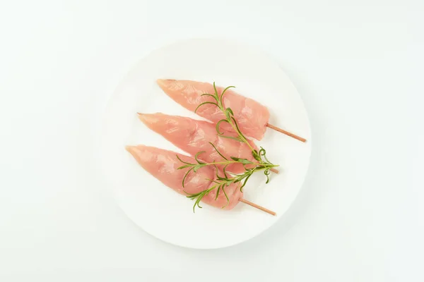 Food concept.Chicken skewers.Skewers from raw chicken meat inner fillet on a white plate for a supermarket on a white background.Ogranic food,healthy eating.Food for retail.Top view.