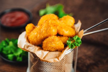 Yarı pişmiş tavuk nuggetları. Koyu bir arka planda taze bitkilerle birlikte tavuk filetosu. Fast food. Evde çabuk pişiyor. Köfteli tavuk filetosu. Hızlı pişirme. Salatalı tavuk nugget..