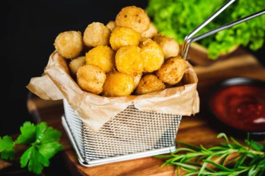 Yarı pişmiş tavuk nuggetları. Koyu bir arka planda taze bitkilerle birlikte tavuk filetosu. Fast food. Evde çabuk pişiyor. Köfteli tavuk filetosu. Hızlı pişirme. Salatalı tavuk nugget..