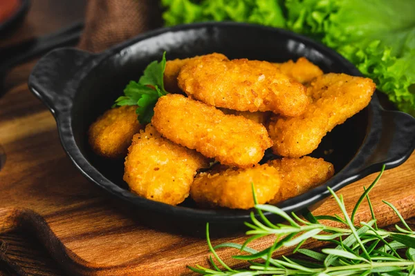 Semifinished Breaded chicken nuggets from chicken fillet on a dark background with fresh herbs.Fast food. Quick cooking at home. Breaded Chicken Inner Fillet. Fast cooking.Chicken nuggets with salad.