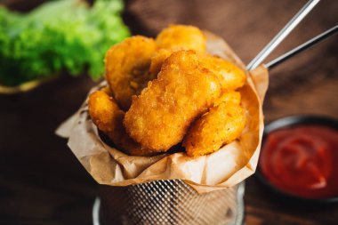 Kızarmış tavuk nugget. Koyu bir arka planda taze otlarla birlikte tavuk filetosundan yarım kalmış tavuk nuggetları. Evde çabuk pişiyor. Fast food. Fırında tavuk filetosu..