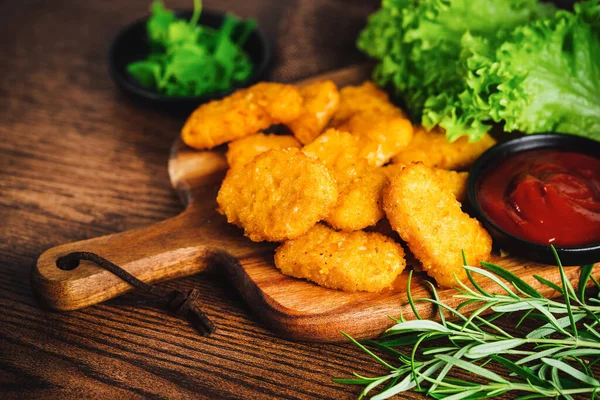 Chicken Breaded Raw Meat.Fast food.Fast cooking.Chicken nuggets with salad.Semifinished Breaded chicken nuggets from chicken fillet on a dark background with fresh herbs. Quick cooking at home.