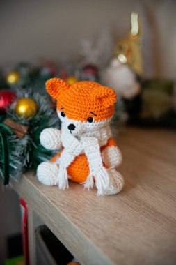 Crochet small handmade fox with a scarf in winter with Christmas decorations