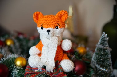 Crochet small handmade fox with a scarf in winter with Christmas decorations