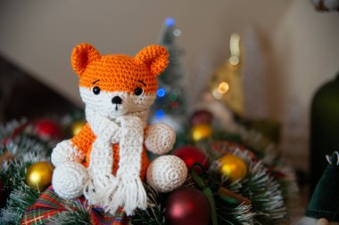 Crochet small handmade fox with a scarf in winter with Christmas decorations