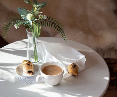 Güneşli sabahlarda kahvaltı: Kafenin iç kısımlarında kahve ve kruvasan, bitkiler ve buğdayla süslenmiş.