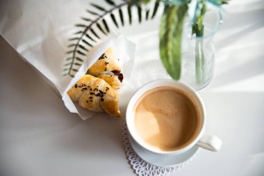 Güneşli sabahlarda kahvaltı: Kafenin iç kısımlarında kahve ve kruvasan, bitkiler ve buğdayla süslenmiş.