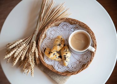 Güneşli sabahlarda kahvaltı: Kafenin iç kısımlarında kahve ve kruvasan, bitkiler ve buğdayla süslenmiş.