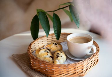 Güneşli sabahlarda kahvaltı: Kafenin iç kısımlarında kahve ve kruvasan, bitkiler ve buğdayla süslenmiş.