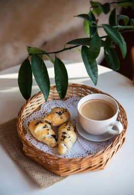 Güneşli sabahlarda kahvaltı: Kafenin iç kısımlarında kahve ve kruvasan, bitkiler ve buğdayla süslenmiş.