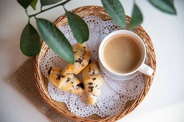 Güneşli sabahlarda kahvaltı: Kafenin iç kısımlarında kahve ve kruvasan, bitkiler ve buğdayla süslenmiş.