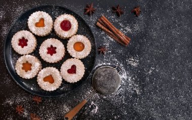 Kayısı ve koyu arkaplanda çilek reçelli ev yapımı Noel Linzer kurabiyeleri. Üst Manzara. Düz yatıyordu.
