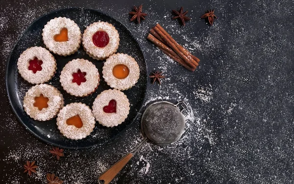 Kayısı ve koyu arkaplanda çilek reçelli ev yapımı Noel Linzer kurabiyeleri. Üst Manzara. Düz yatıyordu.