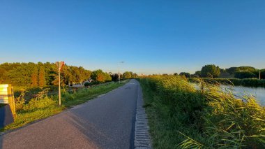 Hollanda Rotterdam yakınlarındaki Oud Verlaat 'ta Rotte nehri boyunca hendeğin üzerinde gün batımı