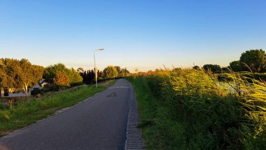 Hollanda Rotterdam yakınlarındaki Oud Verlaat 'ta Rotte nehri boyunca hendeğin üzerinde gün batımı