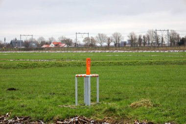 Savunma boru hattı organizasyonu DPO 'nun Zuidplaspolder' da gazyağı ile boruyu işaretlemesi için çayırdaki turuncu direk.