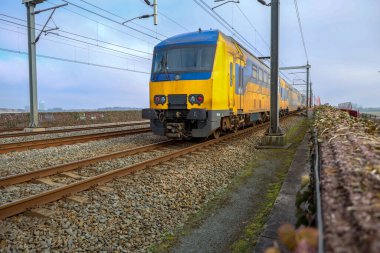 Hollanda 'da DDAZ Doubledeck treni ile Hatem ve Zwolle arasındaki IJssel nehri üzerindeki Hanzeboog adlı kırmızı çelik köprü.