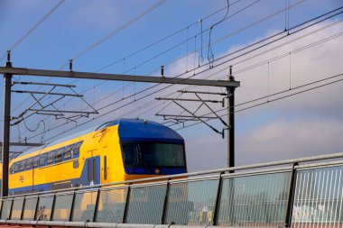 Hatem ve Zwolle arasındaki IJssel nehri üzerinde Hanzeboog adlı kırmızı çelik köprü Hollanda 'da DDAZ çifte güverte sprinter treniyle