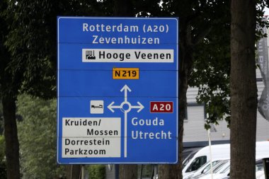 Nieuwerkerk aan den IJssel 'deki A20 otoyolu ile Rotterdam ve Gouda kavşağında mavi yol işaretleri.