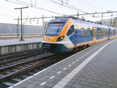 NS SNG yerel banliyö treni Hollanda 'daki Amsterdam Merkez İstasyonu' na varıyor.