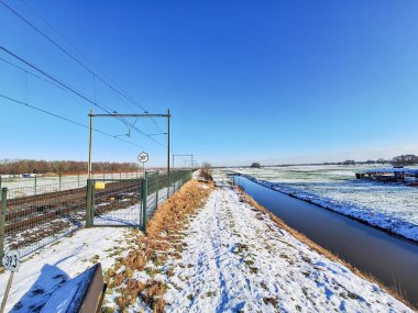 Hollanda 'daki demiryolu raylarının yakınındaki Zuidplaspold' un arta kalan turba bölgesinde kar bulunan donmuş çayırlar.