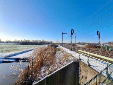 Hollanda 'daki demiryolu raylarının yakınındaki Zuidplaspold' un arta kalan turba bölgesinde kar bulunan donmuş çayırlar.