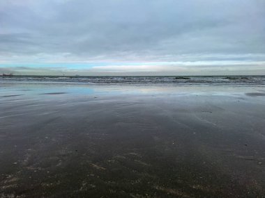 Kuzey Denizi kıyısında Hoek van Holland 'da bulutlu gökyüzü ve Hollanda kıyılarında alçak gelgitle